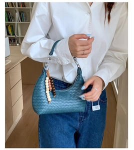 Close-up of teal woven leather hobo bag with unique wooden bead tassel detail