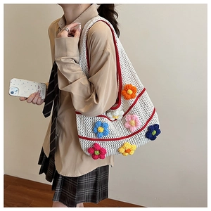 Détail d'un sac cabas en crochet blanc avec fleurs 3D et motifs à rayures rouges