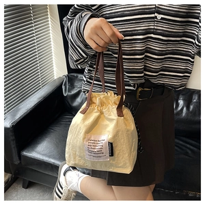Detail of a creamy yellow drawstring lunch bag with brown handles in a lifestyle setting