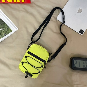 Detailed view of the neon yellow nylon crossbody bag with black cord and zipper
