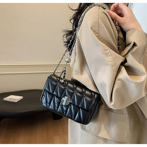 Close-up of quilted black crossbody bag with silver rotating lock and chain strap