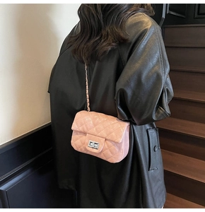Vue détaillée du sac matelassé rose avec fermoir rotatif argenté sur l'épaule du modèle