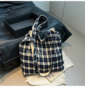 Detail of blue plaid canvas tote with FORYOUG embroidery on a stylish leather sofa