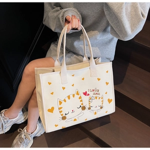 Détail du sac cabas en toile blanche avec illustration de chat rayé jaune et de cœurs