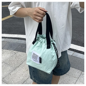 Detail of mint green insulated lunch bag with drawstring handles and woven textile labels