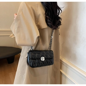 Detail of black quilted leather shoulder bag with silver chain strap and metal buckle