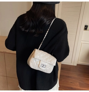 Détail du sac à chaîne beige matelassé porté en bandoulière avec fermoir rotatif
