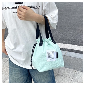 Detail of mint green drawstring lunch bag with ArtisticSoul label and black handles