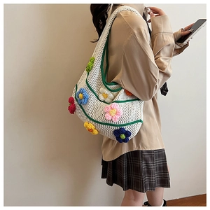 Détail d'un sac bandoulière blanc en maille avec fleurs 3D au crochet et bord vert