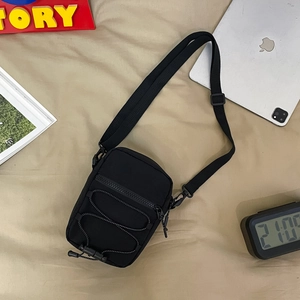Detail of black nylon crossbody bag with adjustable elastic cords and tactical utility design