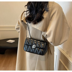 Close-up of black quilted shoulder bag with silver twist lock and chain strap
