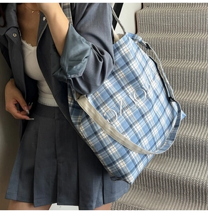 Detail of blue checkered canvas tote bag with white DIJOYO embroidery and woven straps