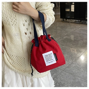 Detail of red drawstring canvas lunch bag with decorative patch and nylon handles