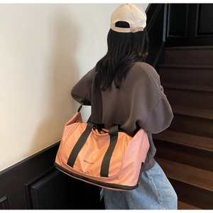 Pink waterproof travel bag with bottom compartment shown by a model on stairs