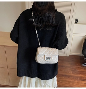 Sac bandoulière matelassé avec fermoir rotatif argenté et chaîne porté par un modèle