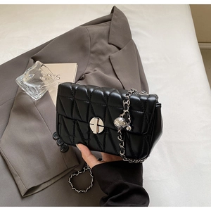 Detailed close-up of a black quilted leather shoulder bag with silver chain strap and metal lock