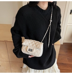 Gros plan du sac bandoulière en cuir blanc matelassé avec chaîne argentée et fermoir