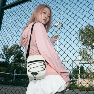 Outdoor shot of a stylish white nylon crossbody bag against a clear blue sky background