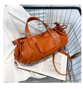 Close-up of orange pleated baguette bag with lychee texture and silver metal buckle