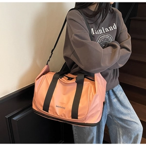 Action shot of the pink expandable duffel bag being carried with the adjustable shoulder strap