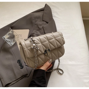 Detail of beige quilted shoulder bag with chain strap and metallic twist-lock closure