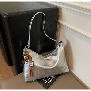 Close-up of silver crescent bag featuring H.SHAN embossed logo and knot charm