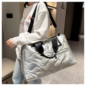Silver quilted tote bag with metallic finish and wide black straps shown on model