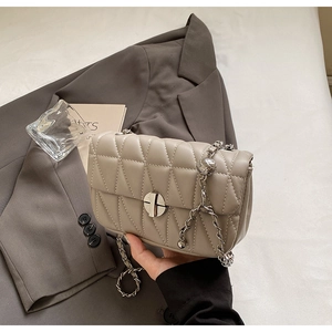 Close-up of quilted pattern stitching and silver circular twist lock on a khaki square bag