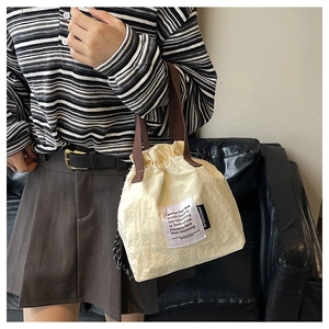 Detail of insulated drawstring lunch bag with pleated texture and stylish webbed handles