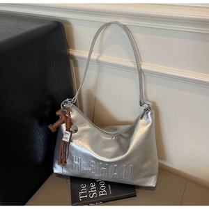 Close-up of silver shoulder bag with embossed texture and a brown horse charm detail
