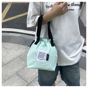 Detail of mint green insulated lunch bag with drawstring closure and black handles