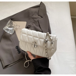 Detail of white quilted faux leather bag with metal chain strap and spherical charm
