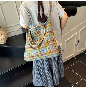 Detail of checkered canvas tote bag with letter embroidery and spacious interior