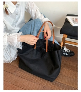 Detail of black canvas tote bag showing interior pocket and brown leather handles