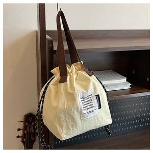 Detail of off-white insulated lunch bag featuring drawstring closure and woven handles