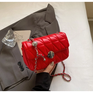 Detail of red quilted leather bag with silver chain strap and hollow metal ball charm