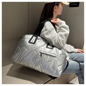 Spacious silver metallic quilted travel tote bag shown with model for size reference