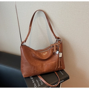 Detail of brown leather handbag featuring embossed lettering and a brand tag charm