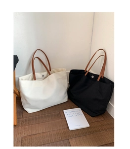 Detail of canvas tote bags in black and beige with magnetic closure and brown straps
