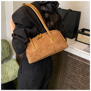 Detail of caramel suede hobo bag featuring contrast white stitching and leather straps