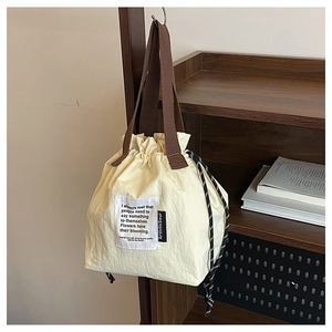 Detail of cream drawstring lunch bag with woven handles and artistic fabric label text
