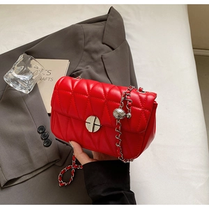 Detail of red quilted leather crossbody bag with silver clasp and chain strap