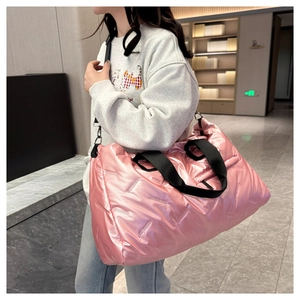 Detailed view of pink quilted puffer tote bag with metallic finish worn by a model