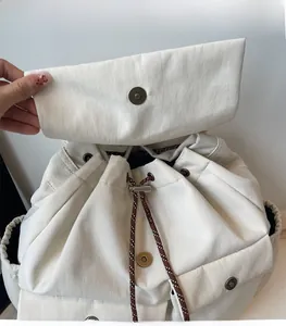 Detail of cream drawstring backpack showing strong magnetic buckle and closure