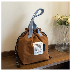 Detail of drawstring bucket lunch bag with blue handles and brown canvas texture