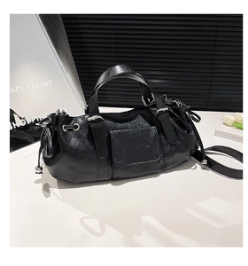 Close-up of black pleated leather handbag featuring silver hardware and side drawstring details
