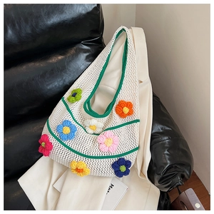 Détail d'un sac cabas en tricot blanc avec fleurs 3D colorées sur un canapé en cuir
