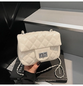 Détail du sac bandoulière matelassé crème avec fermoir rotatif argenté et chaîne