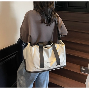 Detail of white glossy travel bag with reinforced strap hooks on a wooden staircase