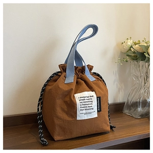 Detail of drawstring bucket lunch bag with artistic text and soft blue woven handles
